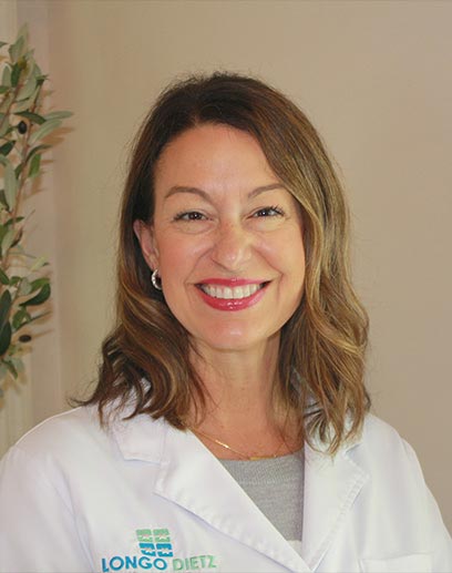 The image features a woman wearing a white lab coat with a name tag, standing indoors, posing for a portrait.